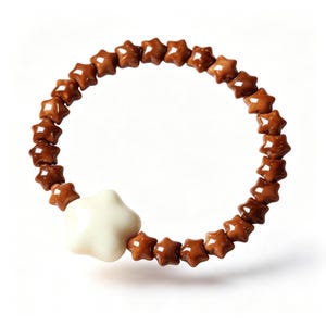 May include: A circular bracelet composed of small, glossy brown star-shaped beads arranged in a continuous loop, featuring one larger, smooth, cream-colored star-shaped bead positioned as a focal point within the strand of brown stars.