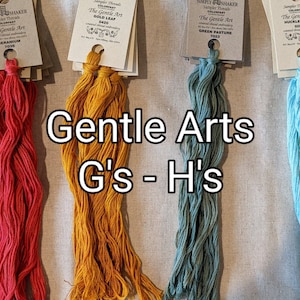 May include: Four skeins of embroidery floss in the colors red, yellow, teal, and light blue. The floss is labeled with the brand name "The Gentle Art" and the color names "Geranium", "Gold Leaf", "Green Pasture", and "Huckleberry". The text "Gentle Arts G's - H's" is written below the skeins.