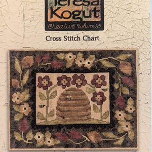 May include: Cross stitch pattern chart for a bee-utiful garden with a beehive, flowers, and bees. The chart is titled "XS164 - Bee-utiful Garden" and includes instructions to stitch 2 over 2 on 30 count linen, with a finished size of 9 by 6.5 inches.