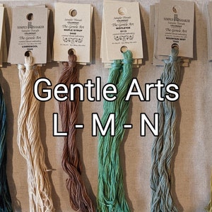 May include: Six spools of embroidery floss in various colors, including teal, beige, brown, green, blue-green, and yellow. The spools are labeled with the brand name "Simply Shaker" and the name of the color. The text "Gentle Arts L-M-N" is written below the spools.