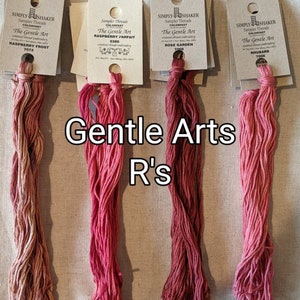 May include: Four spools of embroidery floss in shades of pink and red. The spools are labeled with the brand name "Simply Shaker" and the text "The Gentle Art". The floss colors are Raspberry Frost, Raspberry Parfait, Rose Garden, and Rhubarb.