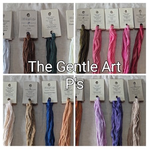 May include: A collection of embroidery floss spools in various colors, including white, brown, green, pink, blue, orange, and purple. The spools are labeled with the text "The Gentle Art" and the color name.