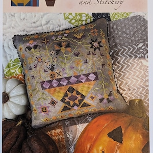 May include: A cross-stitch pattern for a Halloween-themed basket, titled "Betsy's Halloween Basket". The pattern is part of a series called "Betsy's Holiday Baskets". The pattern is designed by Lori Pengelly.