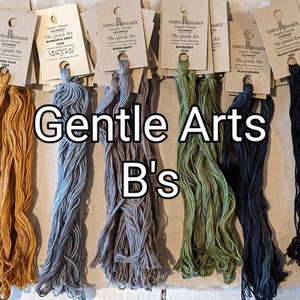 May include: A collection of embroidery floss spools in various shades of green, blue, brown, black, and cream. The spools are labeled "The Gentle Art" and "Simply Threadmaker". The text "Gentle Arts B's" is displayed below the spools.