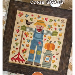 Puede incluir: Patrón de punto de cruz con un espantapájaros acolchado con una calabaza, un rastrillo y hojas de otoño. El patrón se titula "The Quilted Scarecrow" y está diseñado por Lori Holt para Bee in my Bonnet Co.