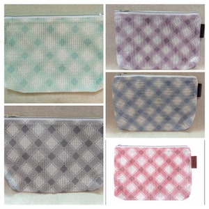 Puede incluir: Cuatro bolsas de malla con cremallera con un patrón de cuadros. Las bolsas son de color azul, rosa, gris y morado.