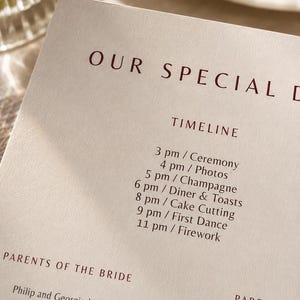 Op de afbeelding: Een crèmekleurige trouwprogrammakaart met donkerrode tekst. De koptekst luidt OUR SPECIAL D, gevolgd door een TIMELINE met evenementen van 3 pm Ceremony tot 11 pm Firework. Daaronder zijn de teksten PARENTS OF THE BRIDE, Philip and Georgia Miller, en MAID OF HONOR, Elena May, zichtbaar.