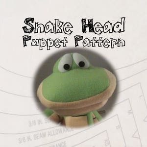 Peut inclure: Un marionnette tête de serpent verte et beige avec de grands yeux ronds. La marionnette est centrée dans un cadre circulaire, avec le texte "Snake Head Puppet Pattern" au-dessus. L'arrière-plan comprend des détails de patron de couture.