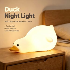 May include: A white duck-shaped night light with a yellow beak and black eyes, emitting a soft warm glow. The text reads: Duck Night Light, Soft Glow Kids Bedside Lamp, Tap Control, Timer Function, 3 Brightness Levels.