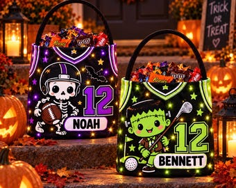 Puede incluir: Dos cubos de tela negra para dulces de Halloween con asas. El cubo izquierdo muestra un esqueleto jugador de fútbol americano, el número 12 y el nombre NOAH. El cubo derecho muestra un monstruo verde, un palo de golf, el número 12 y el nombre BENNETT.