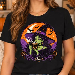 Könnte beinhalten: Ein schwarzes T-Shirt mit einer Grafik einer grünhäutigen Hexe mit langem dunklem Haar und einem violetten Hut. Die Hexe hält eine dampfende Kürbistasse vor einem Hintergrund aus einem großen orangefarbenen Mond, violetten Wolken und schwarzen Fledermäusen.