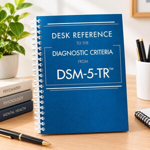 May include: A blue spiral-bound desk reference book titled Desk Reference to the Diagnostic Criteria from DSM-5-TR with white text. The book is positioned upright on a desk next to a stack of three books labeled Psychiatry, Psychology, and Mental Health.
