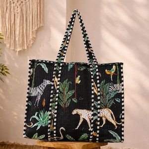 May include: A black quilted tote bag featuring a vibrant jungle print with zebras, leopards, and tropical foliage. The bag has two long handles with a black and white striped pattern that extends down the front and back of the rectangular body.