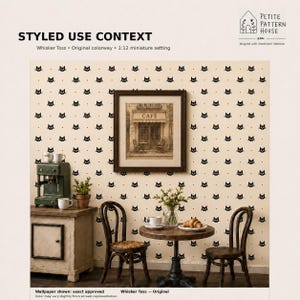 May include: A miniature 1:12 scale setting featuring wallpaper with a repeating black cat face and dot pattern on a cream background. The scene includes a small wooden cabinet, a round table with two chairs, a coffee machine, and a framed cafe print.