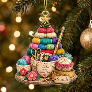 May include: A hanging Christmas ornament shaped like a tree made of stacked colorful yarn balls. It features a gold crochet hook, scissors, a pincushion, and a measuring tape with the text "Sarah" and "Crochet is my Happy Place".