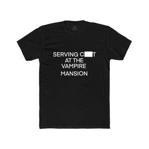 Peut inclure: Un t-shirt noir à manches courtes avec le texte blanc SERVING C[ ]T AT THE VAMPIRE MANSION, où un rectangle blanc masque la lettre U du mot CUNT, imprimé au centre sur la poitrine du vêtement.
