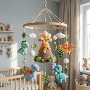Puede incluir: Un móvil de ganchillo para bebé con un volcán central marrón con lava naranja, rodeado de dinosaurios de peluche colgantes en azul, verde y morado, un pterodáctilo naranja volador, nubes blancas y hojas verdes en un marco de madera.