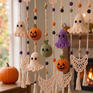 May include: A wall hanging featuring crocheted cream-coloured crescent moon shapes, two orange pumpkins, one green pumpkin, two cream ghosts, and one purple ghost. The figures are suspended from a wooden branch with colourful wooden beads.