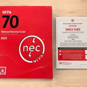 May include: A red NFPA 70 National Electrical Code 2023 edition book featuring a white circular logo with the text nec and lightning bolts, alongside a separate package of index tabs for the 2023 edition and NFPA 70 handbook in a clear plastic sleeve.