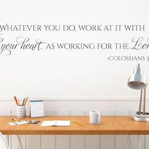May include: A white wall with a black and white inspirational quote that reads "Whatever you do, work at it with all your heart, as working for the Lord. -Colossians 3:23". The quote is displayed on a white wall above a wooden desk with a white mug, a notepad, pencils, and a silver desk lamp.