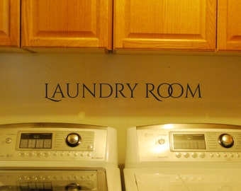 Peut inclure: Une pancarte de buanderie blanche avec le texte "LAUNDRY ROOM" en lettres noires. Deux machines à laver blanches se trouvent sous la pancarte.