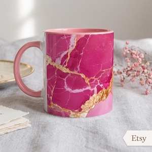 May include: A ceramic mug featuring a vibrant hot pink marble pattern with prominent gold veining throughout the design. The mug has a solid light pink handle and a matching light pink interior rim, providing a consistent color palette.