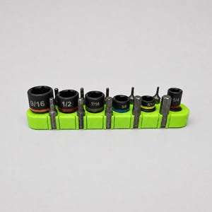 May include: A set of six black metal socket bits with sizes 9/16, 1/2, 7/16, 3/8, 5/16, and 1/4 printed on them, arranged in a bright lime green plastic holder alongside six matching metal hex driver bits in a single row.