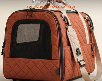 May include: A rust-colored, quilted soft-sided pet carrier featuring black mesh windows, dual top handles, and a detachable padded shoulder strap. The text Pet Carrier, SOFT-SIDED TRAVEL CARRIER, and PADDED SHOULDER STRAP are visible.
