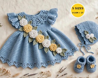 May include: A light blue crochet dress with ruffled sleeves, a matching bonnet, and booties. The set features white and yellow floral appliqués with green leaves. A yellow circular graphic states 5 SIZES 0-24M + 2T.