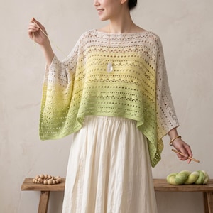 May include: A crochet poncho featuring an ombre color gradient that transitions from a light cream at the top to a vibrant lime green at the bottom. The garment has a wide boat neckline, loose short sleeves, and an intricate openwork pattern.