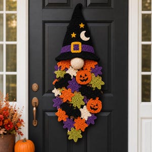 Peut inclure: Une décoration murale en crochet représentant un gnome sorcière avec un grand chapeau pointu noir orné d'une bande violette, d'étoiles jaunes et d'un croissant de lune blanc. La barbe est faite de motifs crochetés : citrouilles orange, chauves-souris noires et étoiles vertes, violettes, orange et crème.