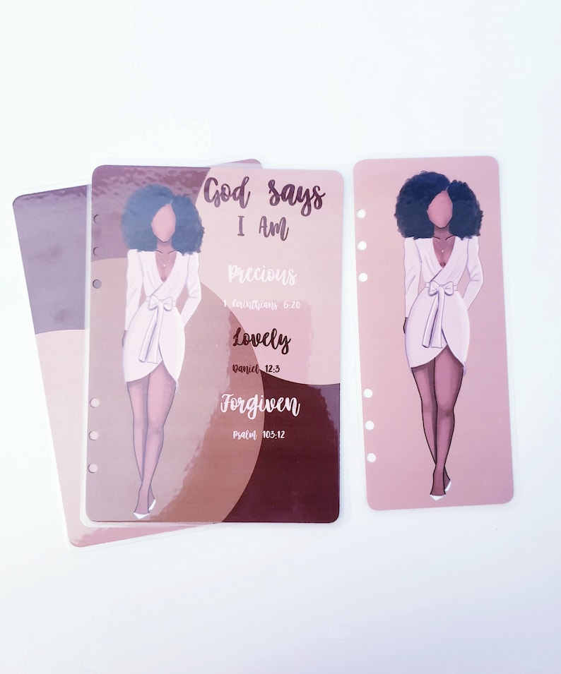 May include: Planner inserts with illustrations of a woman in a white dress. The inserts have text that reads "God says I Am Precious, Lovely, Forgiven" with Bible verses. The inserts are in shades of pink, brown, and white.