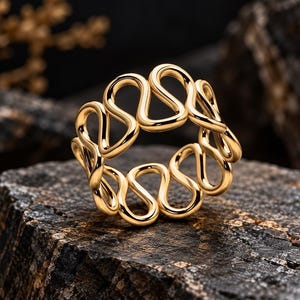 Pode incluir: Um anel de ouro com um padrão contínuo e repetitivo de ondas ou serpentina que forma uma banda vazada. O metal tem uma superfície polida e reflexiva que capta a luz, criando curvas suaves e arredondadas em todo o design.