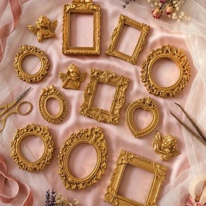 May include: A collection of small, ornate gold-colored picture frames in various shapes including rectangular, oval, and heart-shaped, accompanied by small gold cherub figurines, gold scissors, and metal tweezers on a soft pink fabric background.