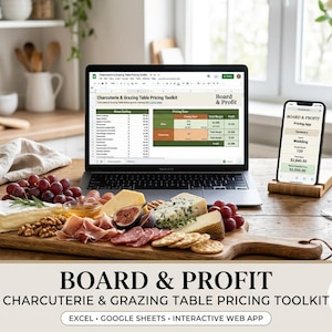 May include: A laptop and a smartphone displaying the Board & Profit Charcuterie & Grazing Table Pricing Toolkit software, positioned behind a wooden serving board filled with cheese, grapes, figs, nuts, and cured meats on a kitchen table.