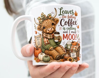 May include: A white ceramic mug featuring a graphic of a fluffy highland cow wearing a plaid scarf and bow, holding a coffee cup. The text reads Leaves are falling Coffee is calling and I must MOO! with pumpkins and autumn foliage accents.