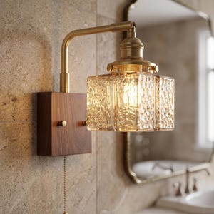 May include: A wall-mounted light fitting featuring a rectangular dark wood base, a brass-toned metal arm, and a square glass shade with a textured, rippled surface. A metal pull chain hangs from the bottom of the wooden base for operation.
