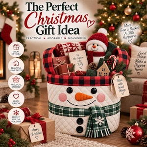 May include: A quilted white fabric storage basket designed to look like a snowman, featuring a black and red buffalo plaid rim, a green plaid scarf, black button eyes, a felt orange carrot nose, and two black buttons on the front.