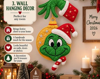Puede incluir: Una decoración de pared acolchada con una mano verde que sostiene un adorno amarillo con una cara verde, un gorro de Papá Noel rojo y un bastón de caramelo. El texto dice 3. WALL HANGING DECOR, Merry Christmas 2026, Home Sweet Holiday, JOY, PEACE, LOVE.
