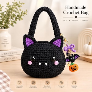 Puede incluir: Un bolso de ganchillo negro hecho a mano con forma de gato, orejas interiores moradas, grandes ojos negros, mejillas rosas y dos colmillos blancos. Un llavero dorado cuelga del lateral con un lazo morado, un pequeño murciélago y una calabaza.