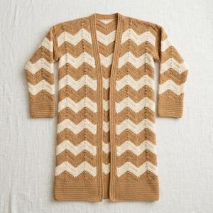 Könnte beinhalten: Eine langärmelige, vorne offene Strickjacke mit einem sich wiederholenden Zickzackmuster in abwechselnden horizontalen Streifen aus Hellbraun und Creme. Das Kleidungsstück hat einen einfarbigen hellbraunen Rand an der Vorderseite, den Ärmeln.