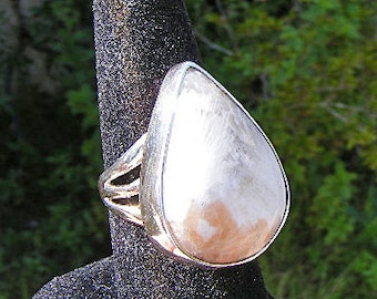 May include: A silver ring with a pearlescent white teardrop-shaped stone.