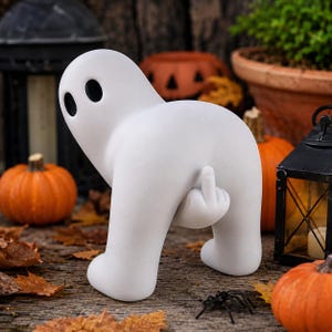 Peut inclure: Une figurine de fantôme blanc mat en position penchée, dotée de deux yeux ovales noirs et d'une main dépassant de son dos pour montrer un doigt d'honneur. La sculpture lisse et arrondie présente une forme minimaliste et une couleur blanche unie.
