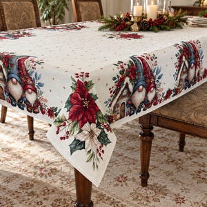 Può includere: Una tovaglia rettangolare con base color crema e un motivo ripetuto di gnomi, casette di pan di zenzero, stelle di Natale rosse e bacche di agrifoglio. Il centro del tessuto è decorato con piccoli puntini marroni regolarmente distanziati.