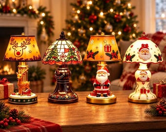 May include: Four decorative table lamps with holiday themes. The first features a reindeer, the second a stained-glass style tree pattern, the third a Santa Claus figure, and the fourth a white base with Santa and gift motifs.