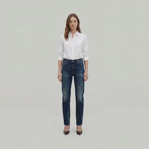 May include: A crisp white long-sleeved button-down shirt with a classic collar paired with dark blue denim jeans. The jeans feature a high-waisted fit, a straight-leg silhouette, and subtle distressed detailing with light paint-like speckles.
