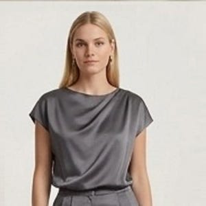 Op de afbeelding: Een antracietgrijze satijnen blouse met een boothals en korte mouwen. De stof heeft een gladde, glanzende afwerking met zachte, gedrapeerde plooien aan de voorzijde, wat zorgt voor een vloeiend silhouet dat op de taille valt.