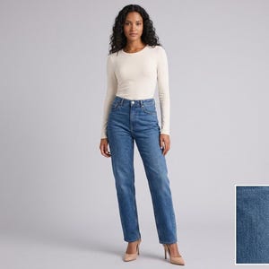 May include: A long-sleeved cream-coloured crew neck top paired with high-waisted blue denim jeans. The jeans feature a classic five-pocket design with a straight-leg cut and a button fly closure. A small inset shows the blue denim fabric texture.
