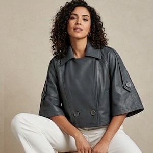 Puede incluir: Una chaqueta corta de color gris carbón con frente de doble botonadura con dos botones grandes, mangas anchas de tres cuartos con trabillas abotonadas, cuello ancho y costuras estructuradas en el frente y los hombros.