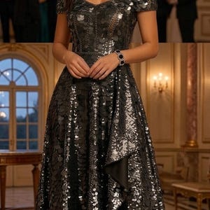 May include: A floor-length off-the-shoulder gown covered in dark, reflective circular sequins. The dress features a sweetheart neckline, a fitted bodice, and a high-low hemline with a layered skirt. It is paired with black strappy high-heeled sandals.